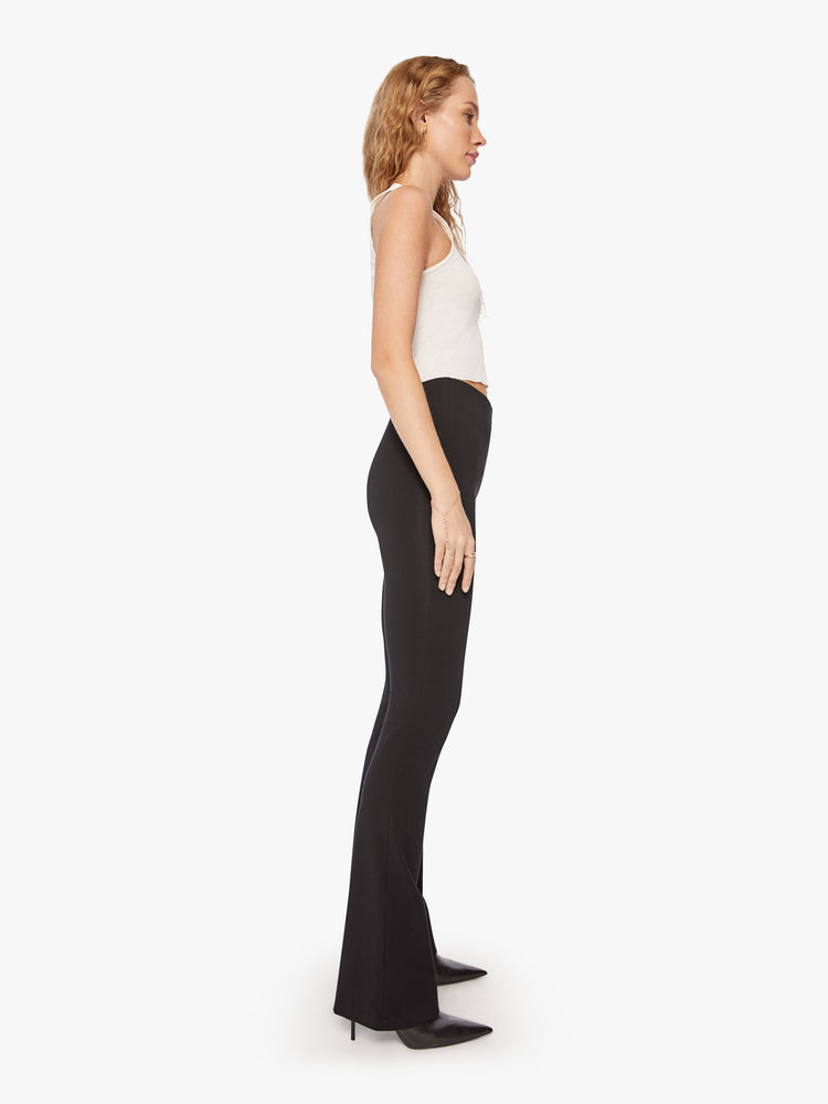 Side full body view of a womens black high rise pant featuring a fitted flare leg.