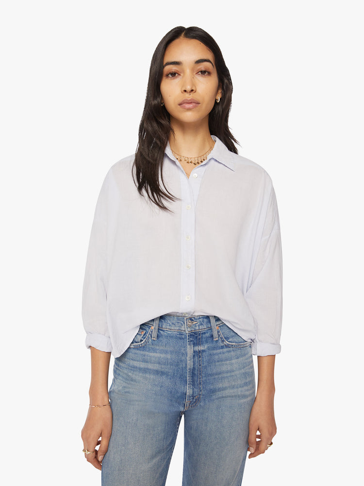 Front view of a woman sky blue collared button-down shirt is designed with long-sleeves, a V-neck and a boxy fit.