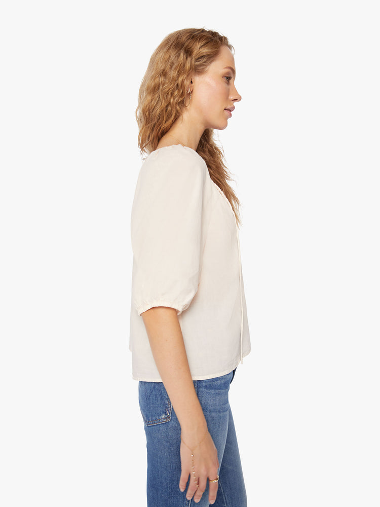 Side view of a woman creamy peach blouse with a gathered scoop neck that ties, 3/4-length balloon sleeves.