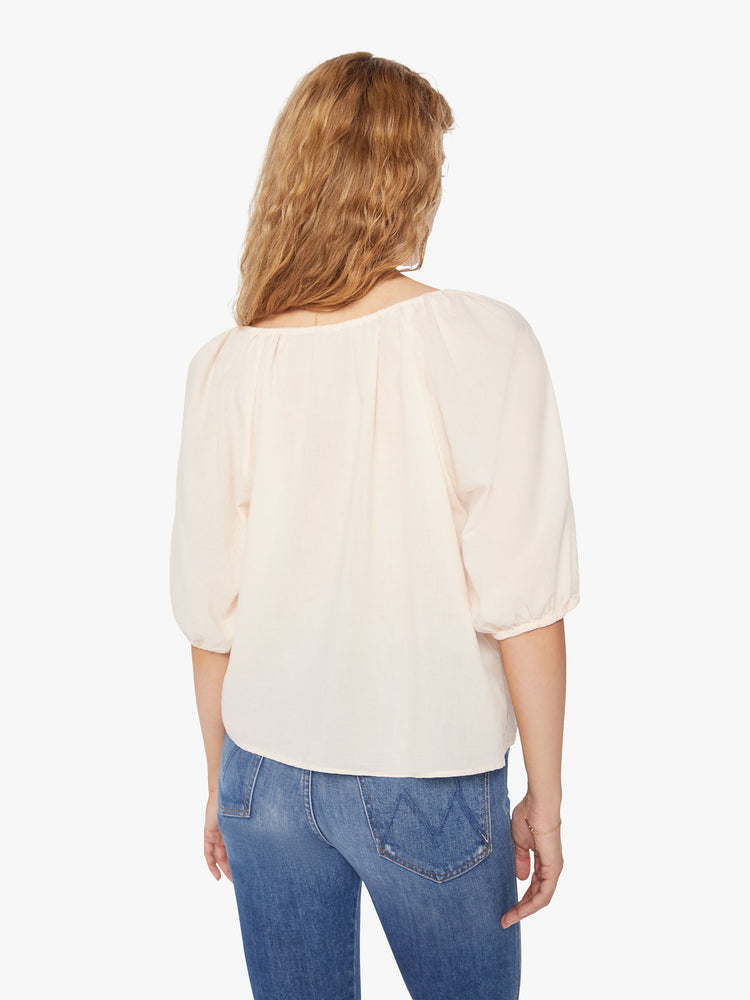 Back view of a woman creamy peach blouse with a gathered scoop neck that ties, 3/4-length balloon sleeves.