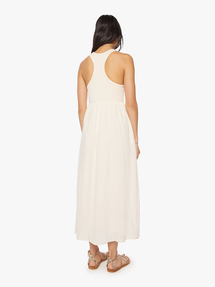 Back view of a woman sleeveless dress is designed with a crew neck, fitted bodice and a high-waisted skirt with ruffles.