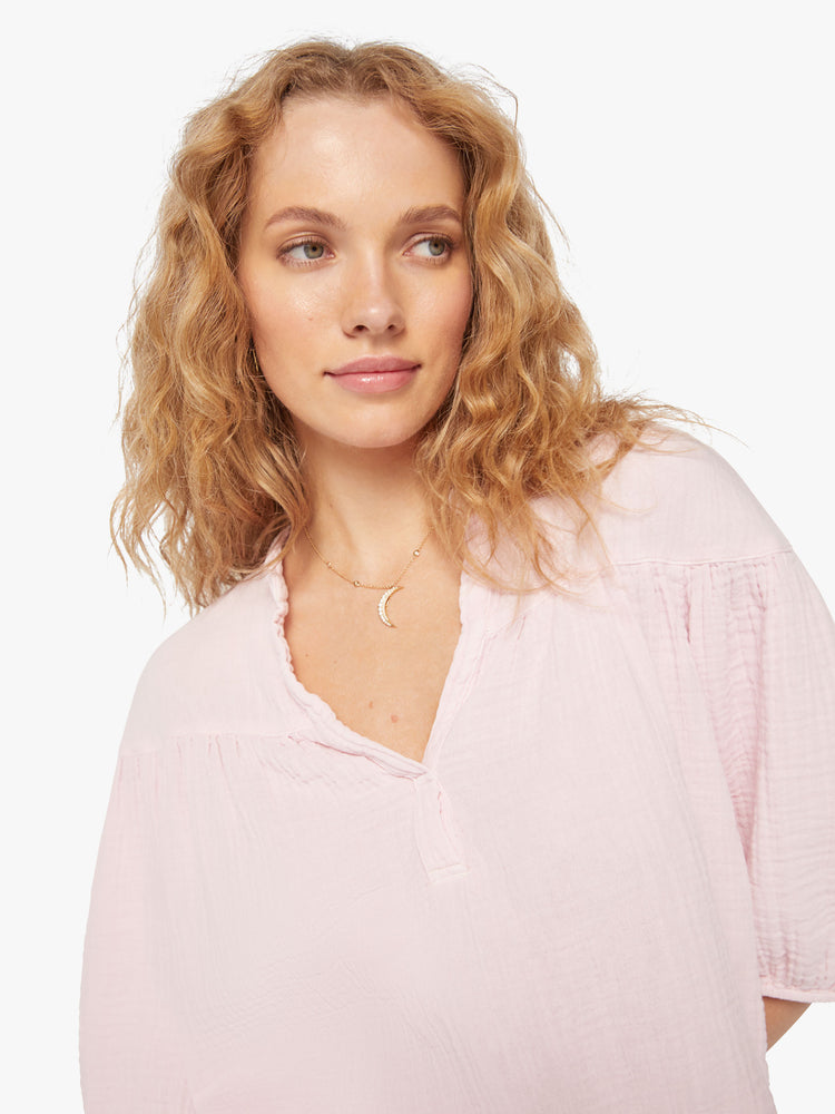 Close up view of a woman baby pink top designed with a V-neck, 3/4-length balloon sleeves.