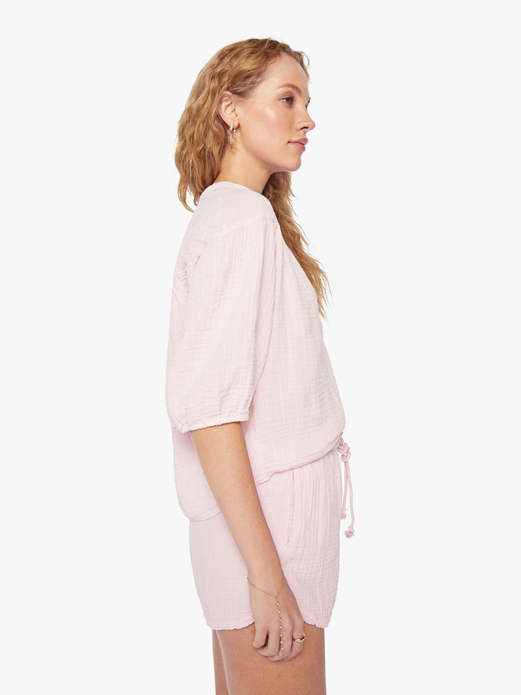 Side view of a woman baby pink top designed with a V-neck, 3/4-length balloon sleeves.