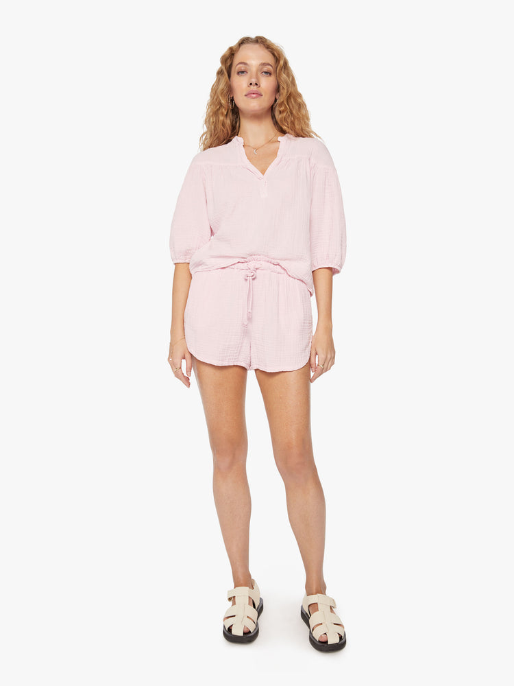 Full body view of a woman baby pink top designed with a V-neck, 3/4-length balloon sleeves.