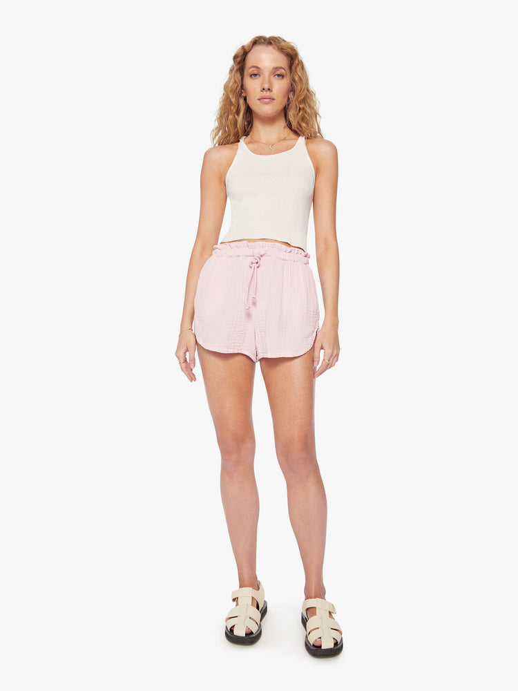 Front view of a woman baby pink short with a drawstring elastic waistband and curved hems.