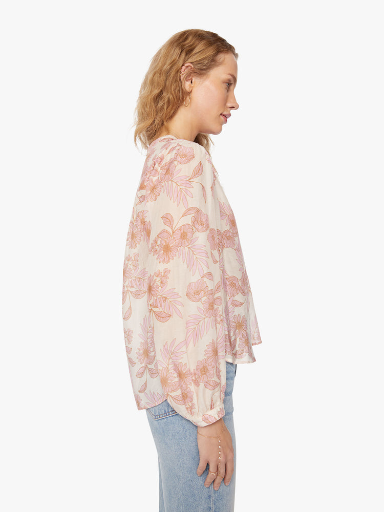 Side view of a woman top designed with a buttoned V-neck, long balloon sleeves and a curved hem.
