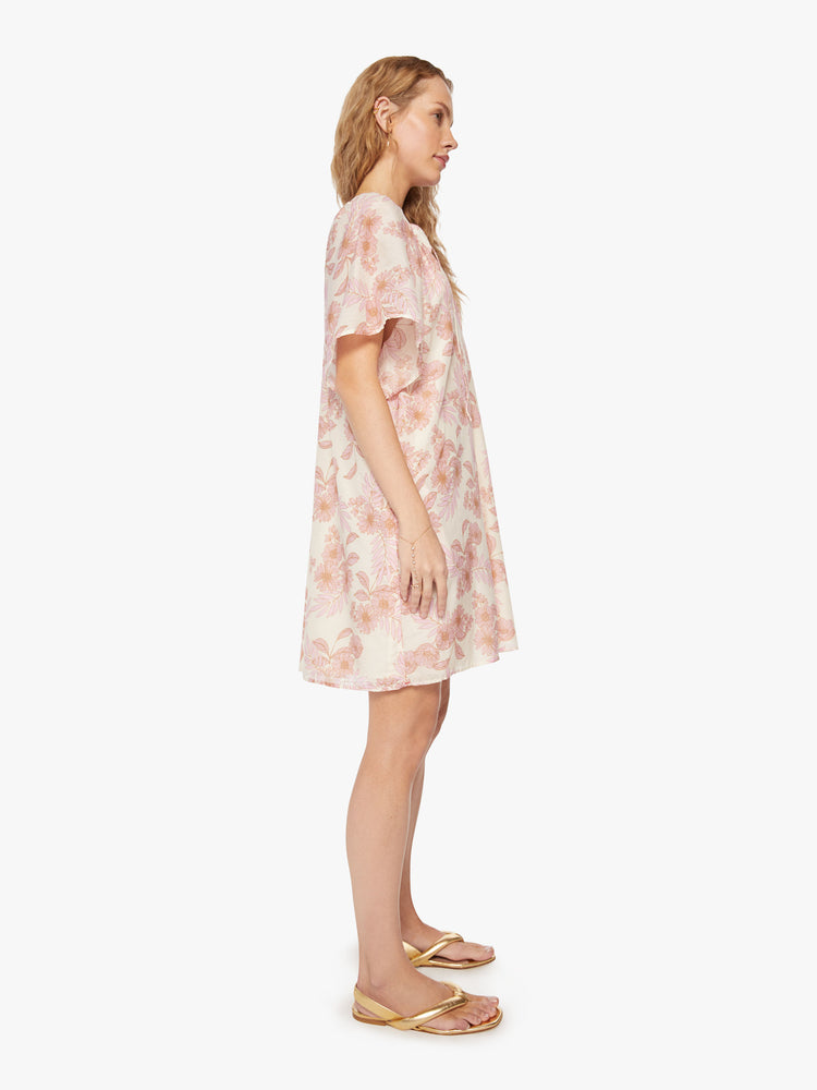 Side view of a woman's dress designed with a keyhole neckline and flowy short sleeves in a pink and orange floral pattern.