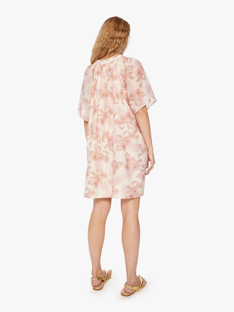 Back view of a woman's dress designed with a keyhole neckline and flowy short sleeves in a pink and orange floral pattern.