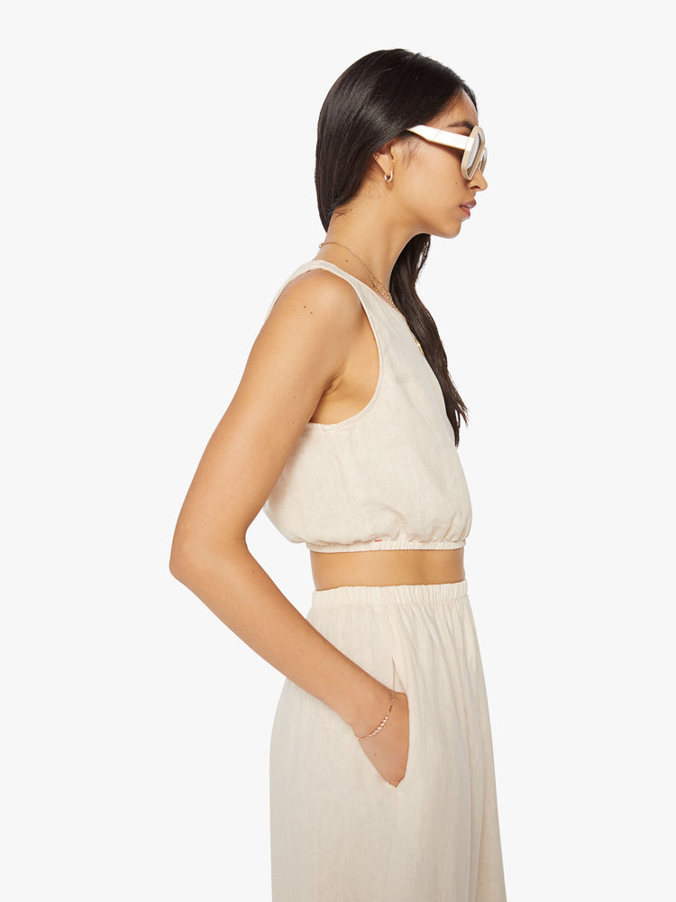 Side view of a woman off white crop top features a crewneck and a cropped elastic hem.