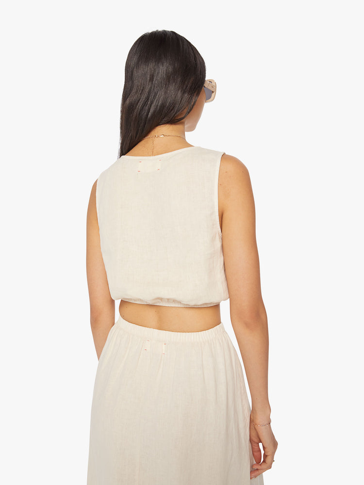 Back view of a woman off white crop top features a crewneck and a cropped elastic hem.