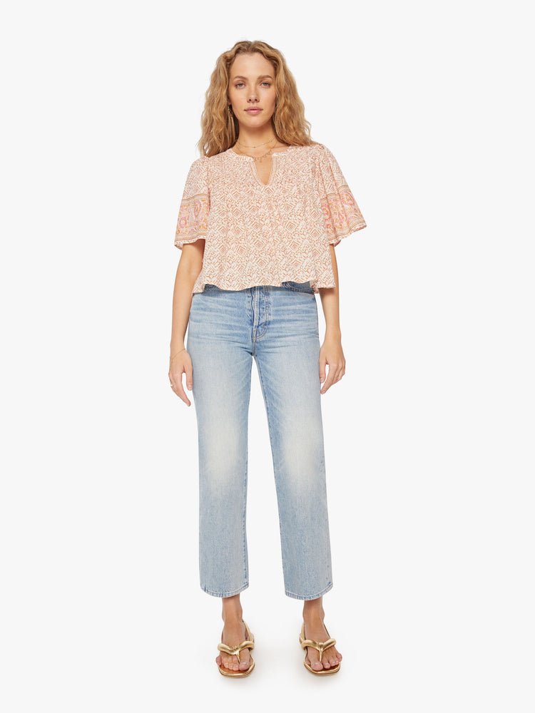 Full body view of a woman pink pattern blouse is designed with a V-neck, short, boxy sleeves and slight cropped hem.