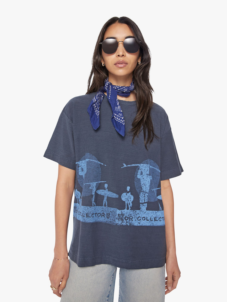 Front view of a woman in black tee with a blue surfer graphic, and features drop shoulders and a boxy fit.