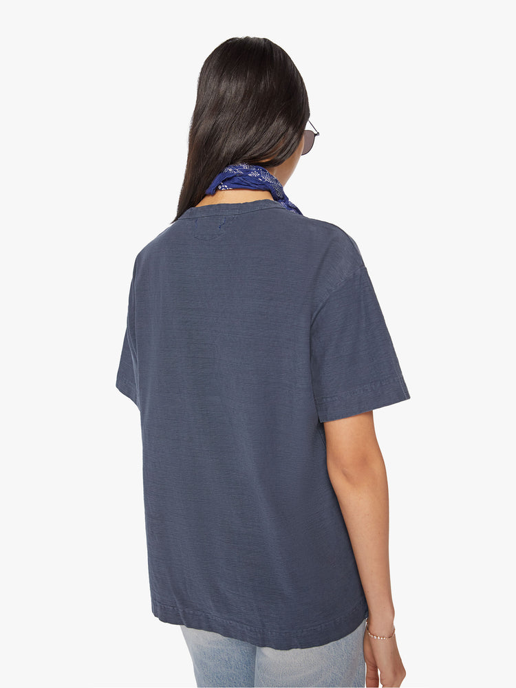 Back view of a woman in black tee with a blue surfer graphic, and features drop shoulders and a boxy fit.