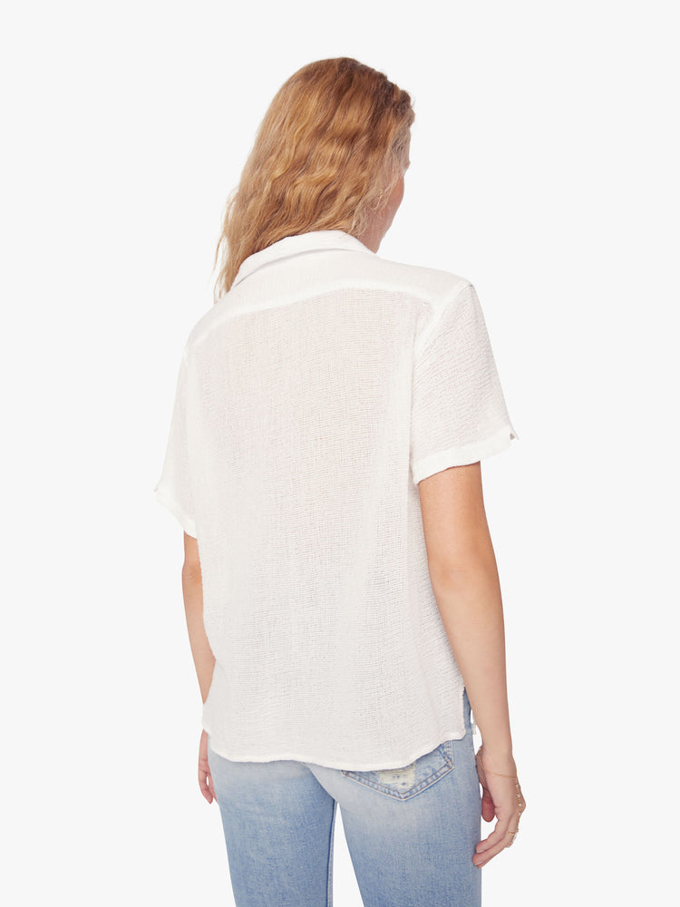 Back view of a woman semi sheer white short-sleeve collared shirt with front patch pockets and boxy fit.