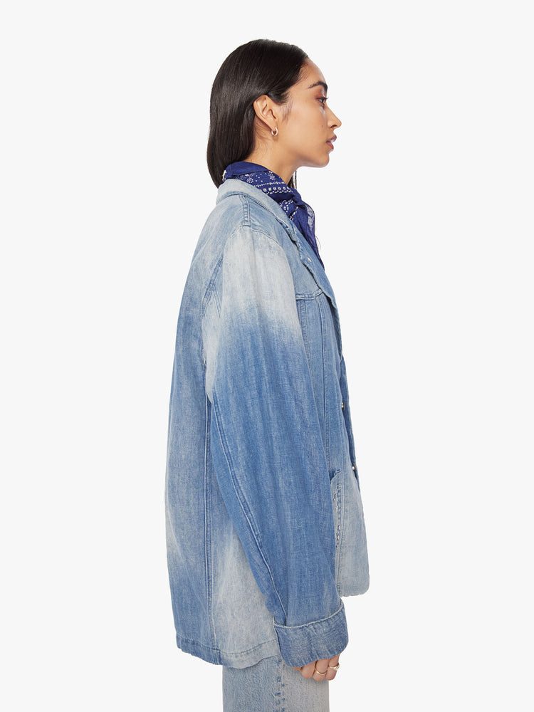 Side view of a woman denim blazer with a notched collar, front patch pockets, buttons down the front in a vintage blue wash.