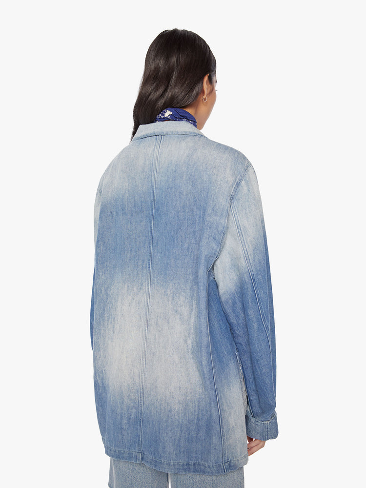 Back view of a woman denim blazer with a notched collar, front patch pockets, buttons down the front in a vintage blue wash.