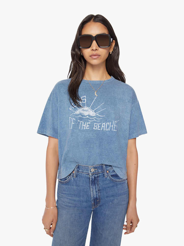 Front view of a woman tee with drop shoulders, a boxy fit in blue with faded white sunset graphic.