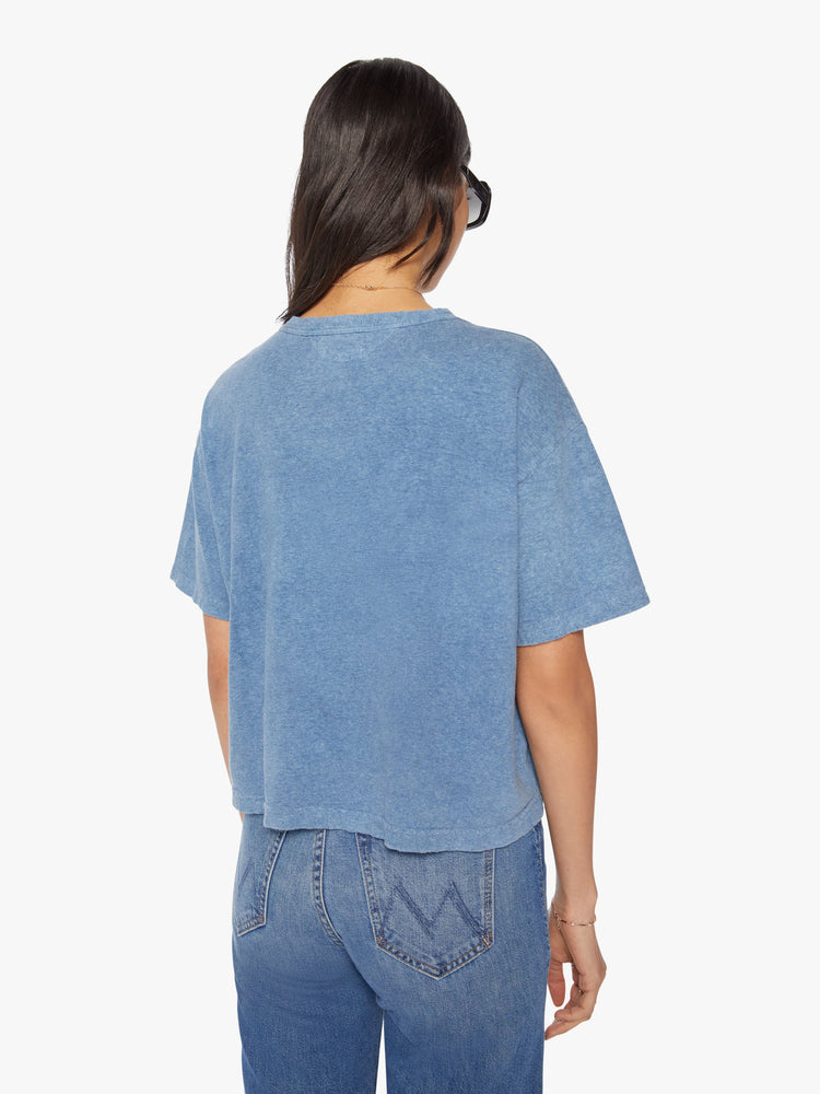 Back view of a woman tee with drop shoulders, a boxy fit in blue with faded white sunset graphic.
