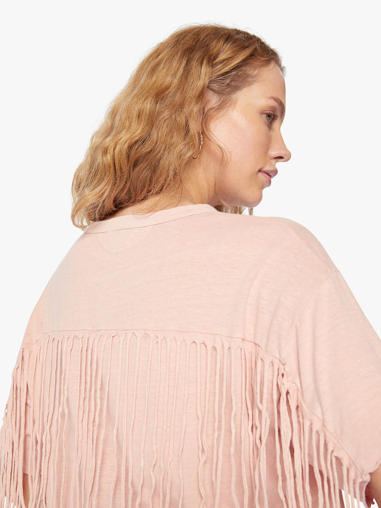 Close up view of a woman crop tee with drop shoulders, a boxy fit in a soft pink hue with fringe across the back.