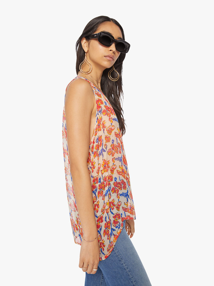 Side view of a woman tank in off-white chiffon with a watercolor floral print in orange and navy with a hip-grazing hem.