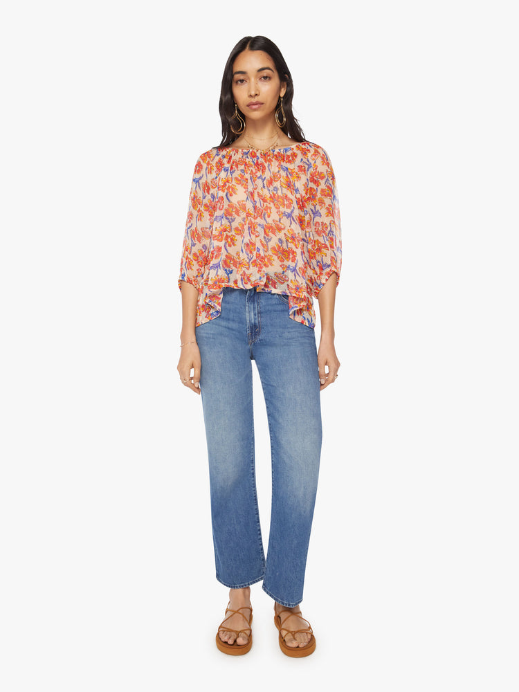 Full body view of a woman's blouse in off-white chiffon with a watercolor floral print in orange and navy and with an elastic boat neck and 3/4-length balloon sleeves.
