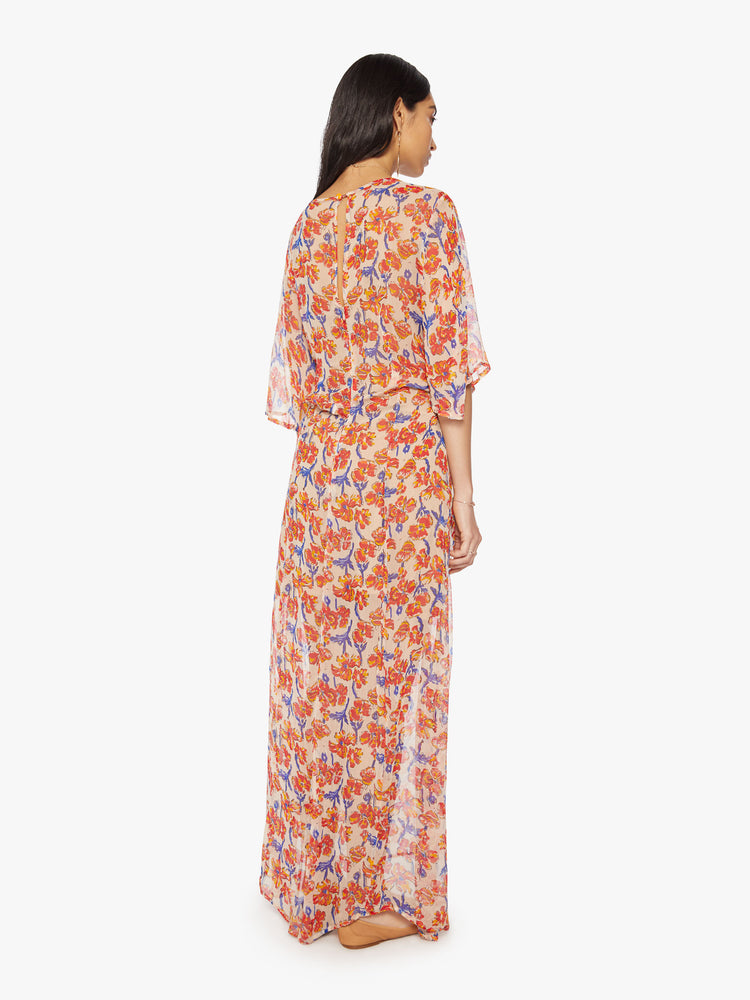 Back view of a woman's maxi dress in an off-white chiffon with a watercolor floral print with a crewneck, elbow-length sleeves, curved waist and ankle length hem.