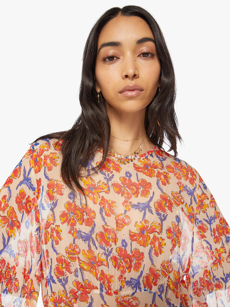 Close up view of a woman's maxi dress in an off-white chiffon with a watercolor floral print with a crewneck, elbow-length sleeves, curved waist and ankle length hem.