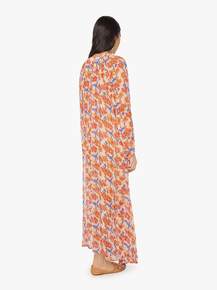 Back full body view of a woman's maxi dress in off-white chiffon with a watercolor floral print in orange and navy with voluminous sleeves and has an A-line cut.