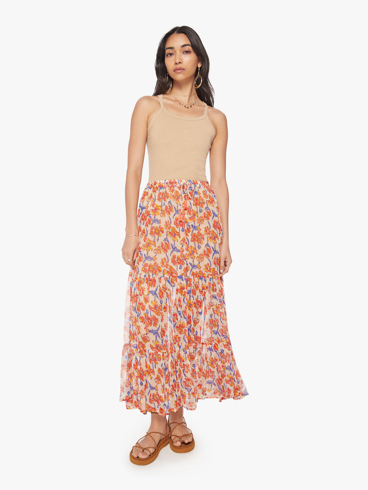 Front view of a woman maxi skirt in an off-white chiffon with a orange/navy watercolor floral print with a drawstring waistband and ruffled hem.