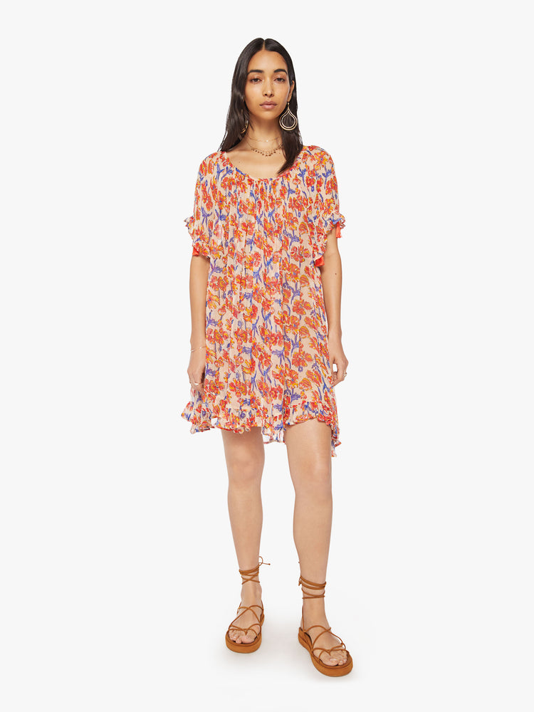 Front view of a woman dress in an off-white chiffon with a watercolor orange/navy floral print with a wide curved neckline and short balloon sleeves.