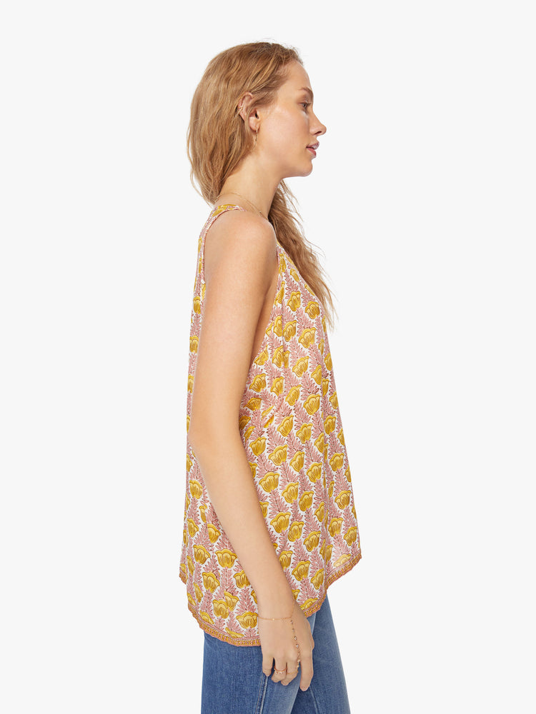 Side view of a woman crewneck tank designed in a pink and yellow tulip print and a hip-grazing hem.