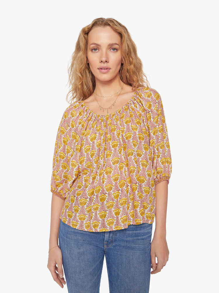 Front view of a woman's blouse in a pink and yellow tulip print and features an elastic boat neck and 3/4-length balloon sleeves.