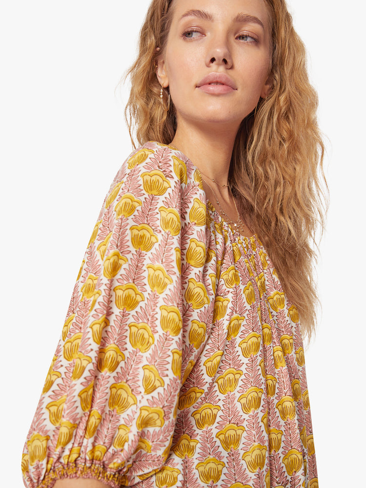 Close up view of a woman's blouse in a pink and yellow tulip print and features an elastic boat neck and 3/4-length balloon sleeves.