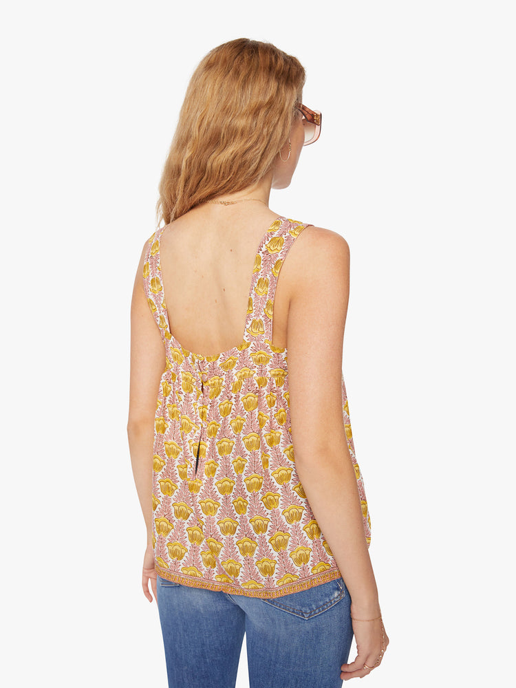 Back view of a woman's top in a pink and yellow tulip print, and detailed straps and buttons in the back.