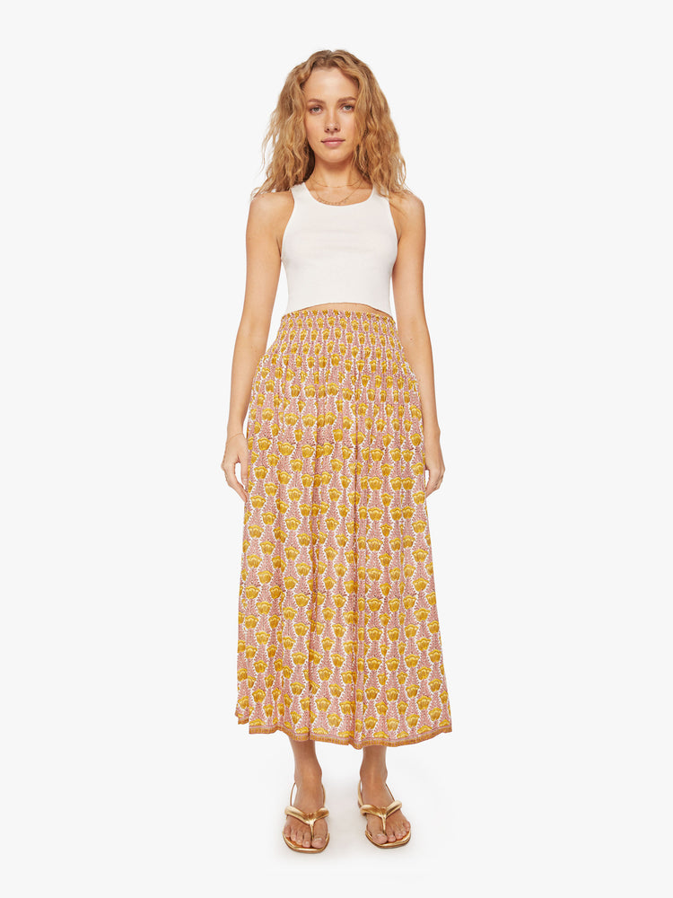 Front view of a woman's maxi skirt in a pink and yellow tulip print and a smocked waistband.