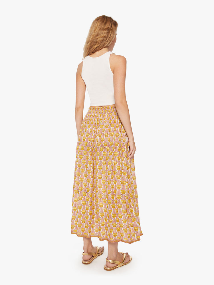 Back view of a woman's maxi skirt in a pink and yellow tulip print and a smocked waistband.