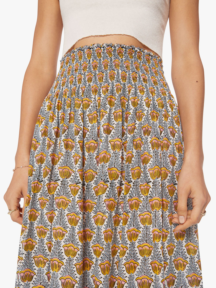 Close up waist view of a woman maxi skirt in a blue and yellow tulip print and a smocked waistband.
