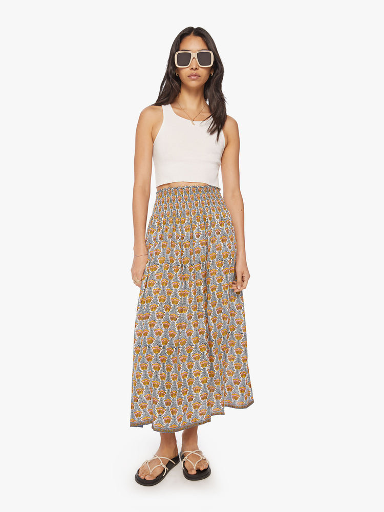 Front view of a woman maxi skirt in a  blue and yellow tulip print and a smocked waistband.