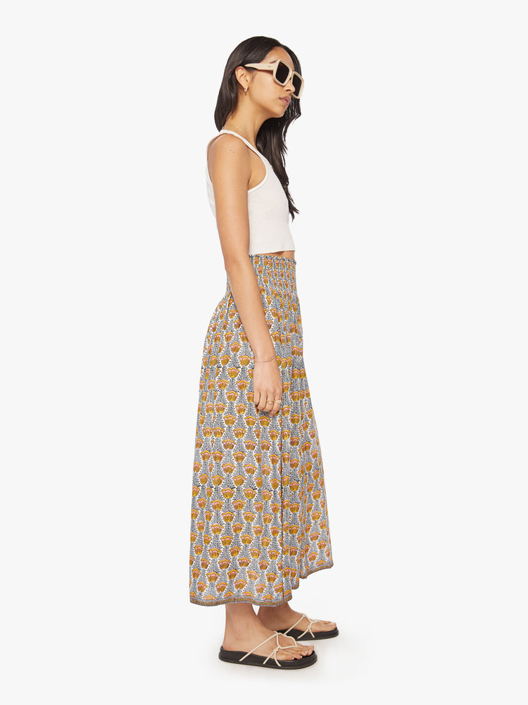 Side view of a woman maxi skirt in a blue and yellow tulip print and a smocked waistband.