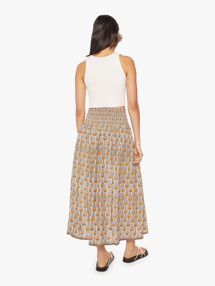 Back view of a woman maxi skirt in a blue and yellow tulip print and a smocked waistband.