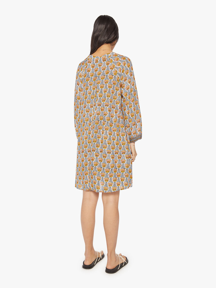 Back view of a woman's maxi dress in blue and yellow tulip print with voluminous sleeves, a deep V-neck with covered buttons.
