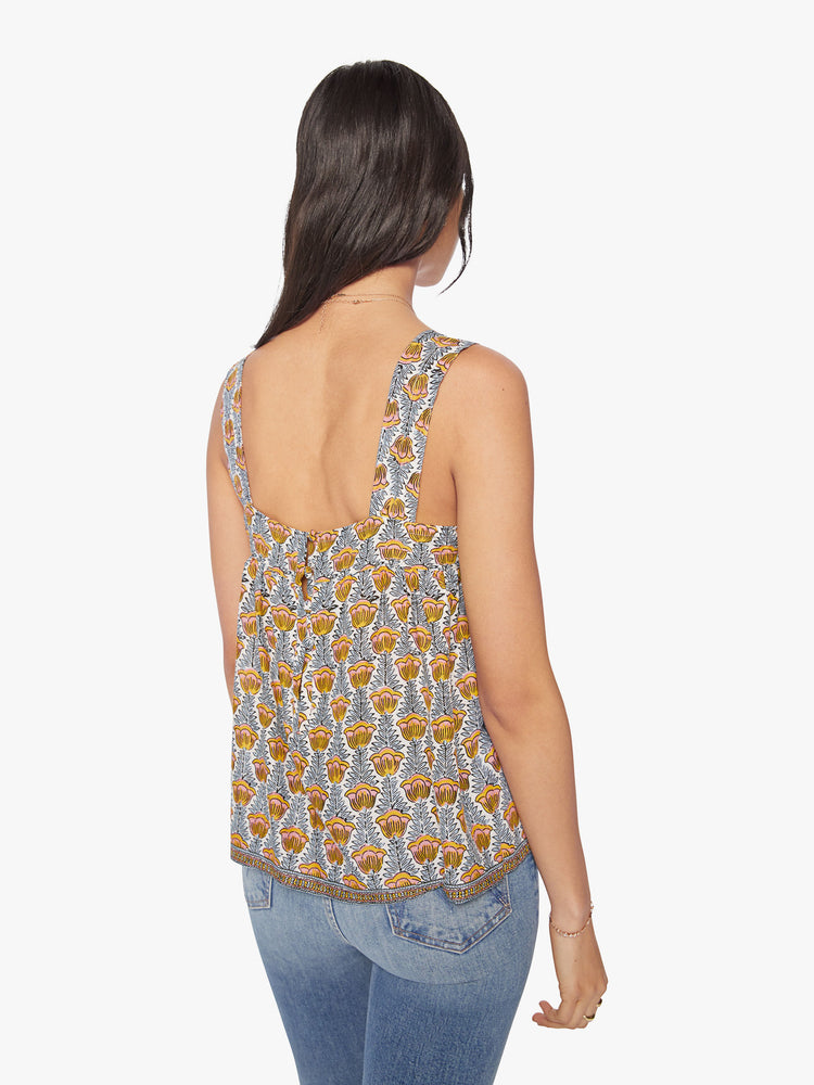 Back view of woman's top in a blue and yellow tulip print, and detailed straps and buttons in the back.