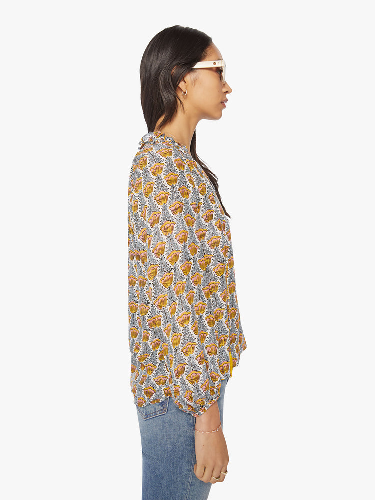Side view of a woman's blouse in blue and yellow tulip print with a keyhole neckline with a tasseled tie closure, long balloon sleeves.
