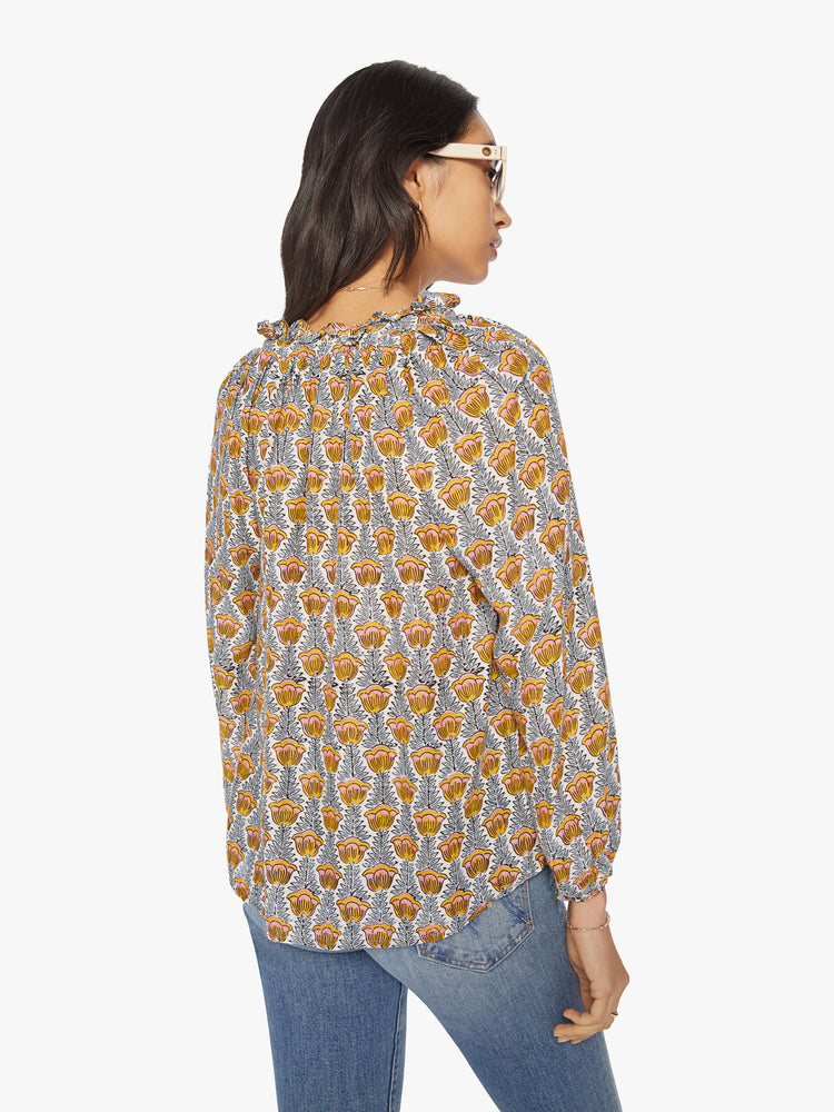 Back view of a woman's blouse in blue and yellow tulip print with a keyhole neckline with a tasseled tie closure, long balloon sleeves.