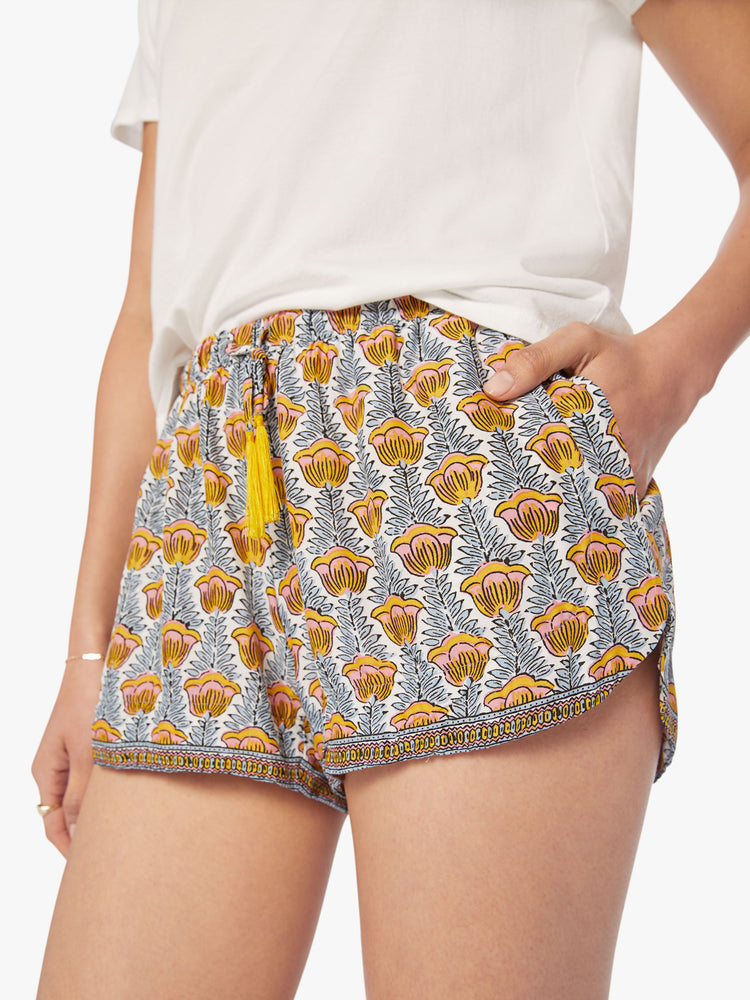 Close up view of a woman blue and yellow tulip print lightweight shorts with an elastic waist with drawstring, side pockets and scalloped hemline.