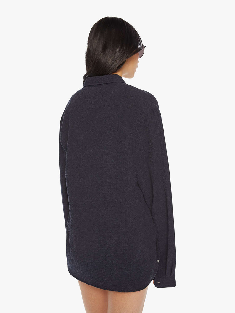 Back view of a woman dark navy long sleeve button-up shirt with a loose, boxy fit.