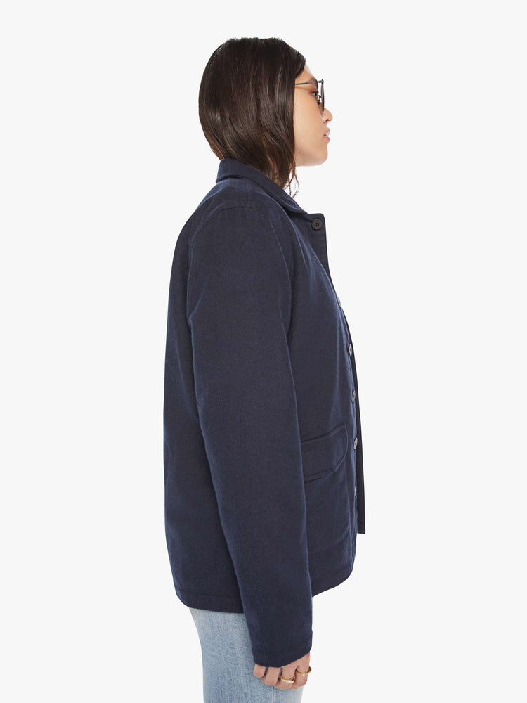 Side view of woman in a dark blue shirt with front patch pockets, long sleeves, buttons down the front and a boxy fit.