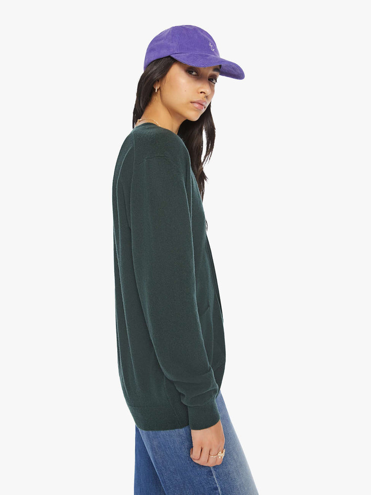 WOMEN side view of knit cardigan in a dark green hue with a V-neck, patch pockets and buttons down the front.