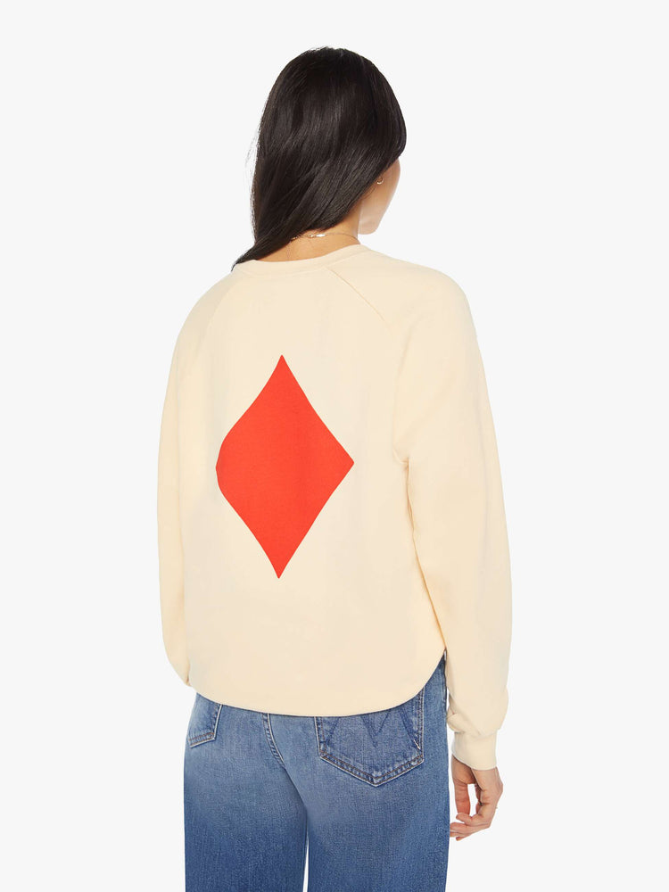 Back view of a woman crewneck sweatshirt in a cream hue with a relaxed shape with raglan sleeves and is decorated with a red diamond graphic on the back and a logo on the front.