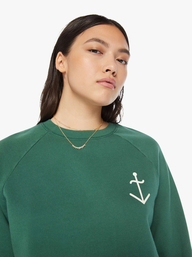 Back view of a woman crewneck sweatshirt in a hunter green hue with a white anchor and has a relaxed shape with raglan sleeves.